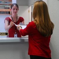 This is a picture of a patient handing paperwork through a window to a nurse.